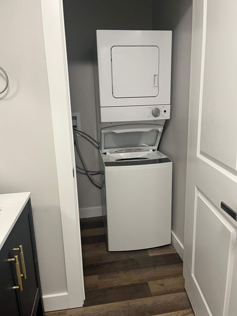 A white dishwasher is in a narrow space between a cabinet and a wall.