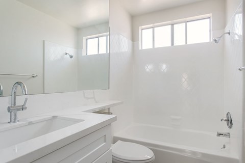 A white bathroom with a toilet, sink, and bathtub.