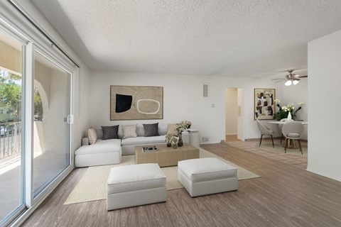 A modern living room with white furniture and a large painting on the wall.