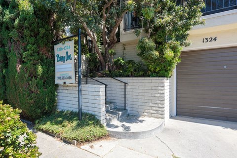 A sign for a business is displayed in front of a building with a closed garage door.