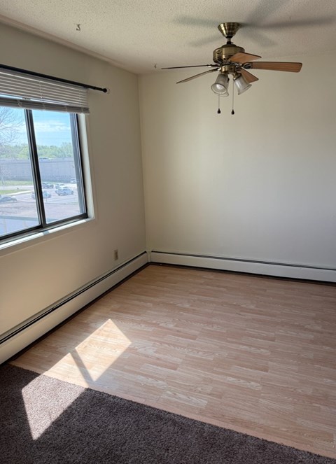 A room with a ceiling fan and a window.