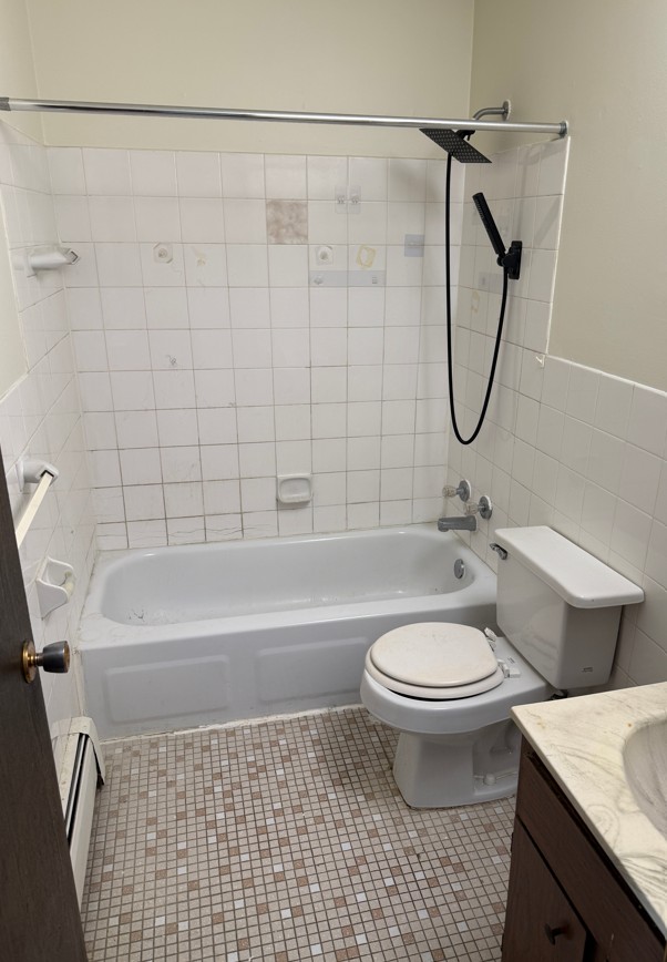 A white toilet sits next to a bathtub in a bathroom.
