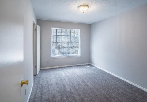 A room with a carpeted floor and a window.