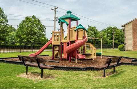 A playground with a red slide and a green roof.