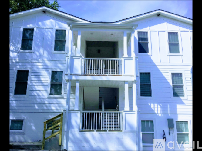 A white two-story apartment building with a balcony on the second floor.