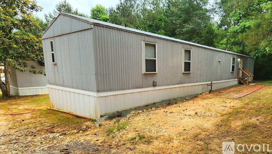 A metal building with a grey exterior is surrounded by trees and grass.