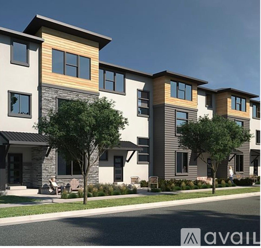 A row of modern townhouses with a clear blue sky above them.