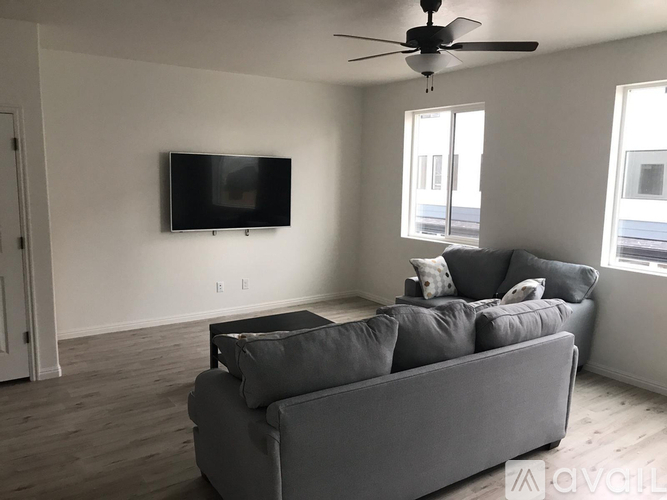 A living room with a grey couch and a flat screen TV mounted on the wall.