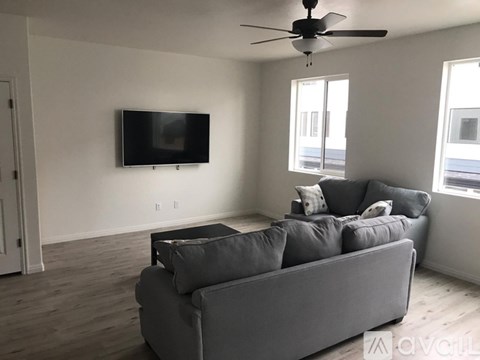 A living room with a grey couch and a flat screen TV mounted on the wall.