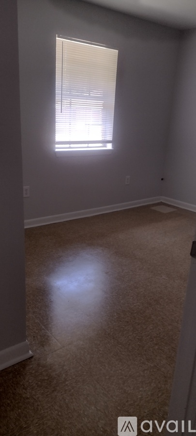 A room with a window and a carpeted floor.