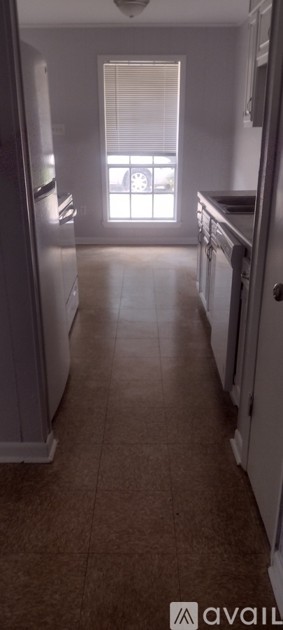 A kitchen with white appliances and brown flooring.