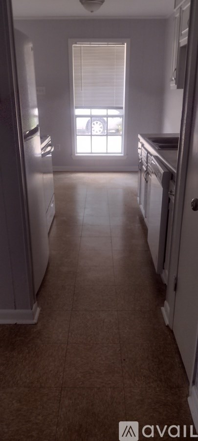 A kitchen with white appliances and brown flooring.
