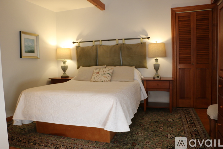 A bedroom with a large bed and two lamps.