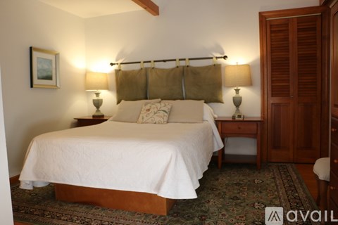 A bedroom with a large bed and two lamps.