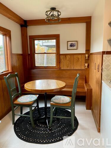 A dining room with a round table and two chairs.