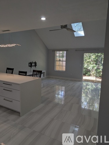 A modern kitchen with a white countertop and a large window.