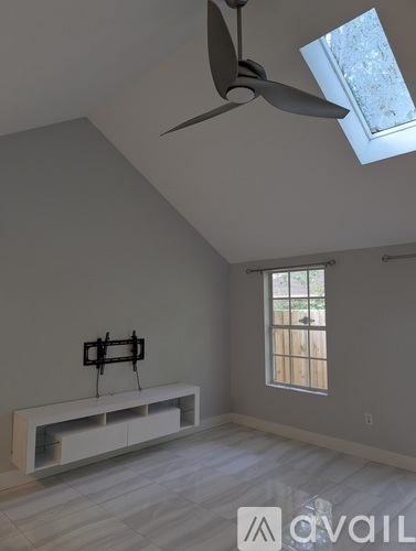 A room with a ceiling fan and a window with bars.