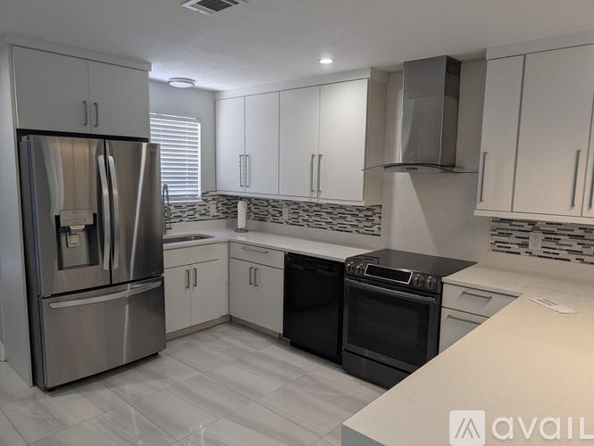 A modern kitchen with a stainless steel refrigerator and black appliances.