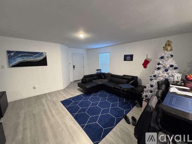 A living room with a Christmas tree and a painting on the wall.