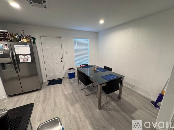 A kitchen with a fridge, table and chairs.