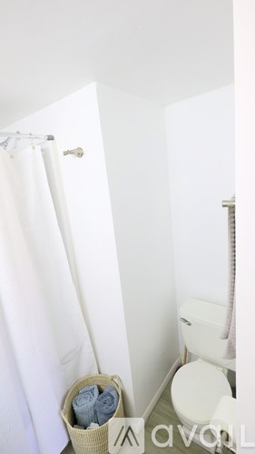 A white toilet sits next to a white shower curtain.