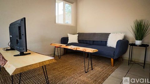 A living room with a blue couch, a wooden table, and a television.