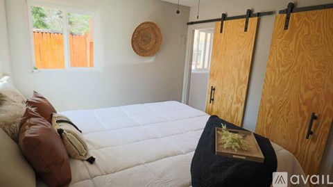 A bedroom with a bed, pillow, and a bag on the bed.