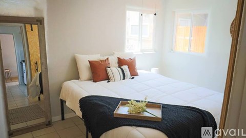A bedroom with a bed, pillows, and a tray with flowers on the bed.