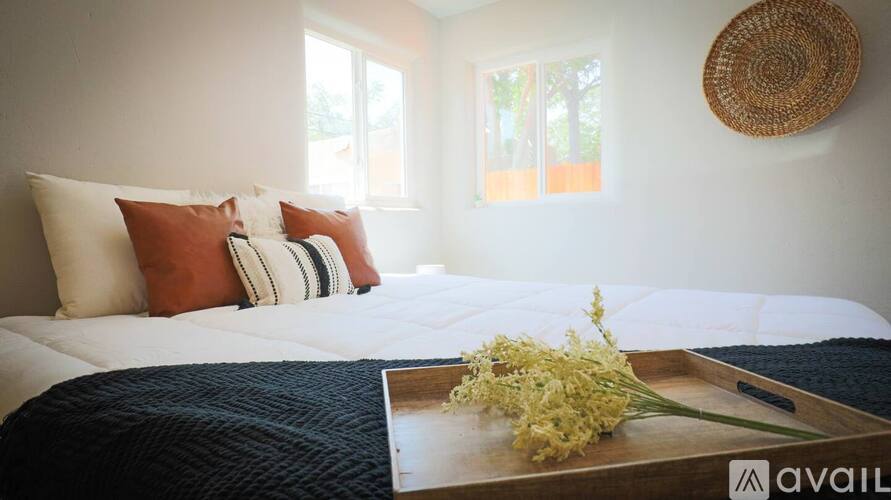 A bed with a white comforter and a tray with flowers on it.