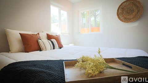 A bed with a white comforter and a tray with flowers on it.