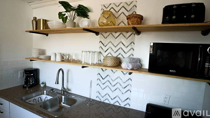 A kitchen with a sink, shelves, and a microwave.