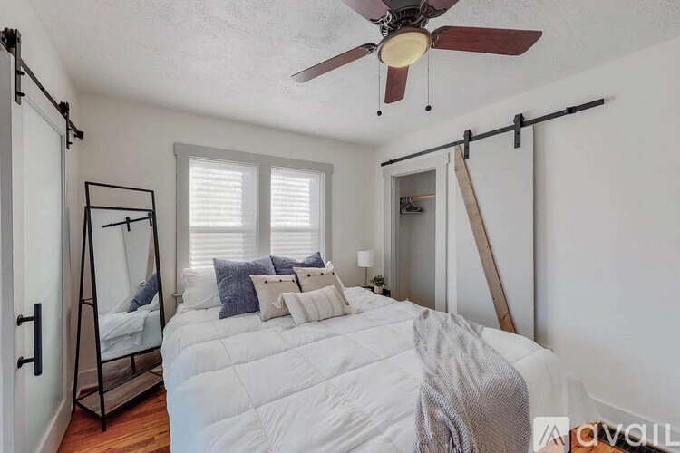 A bedroom with a white bed and a ceiling fan.