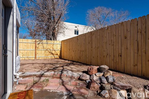 A wooden fence and a pile of rocks in the foreground with a building in the background.