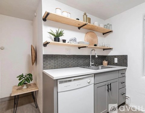 A kitchen with a white dishwasher and grey cabinets.