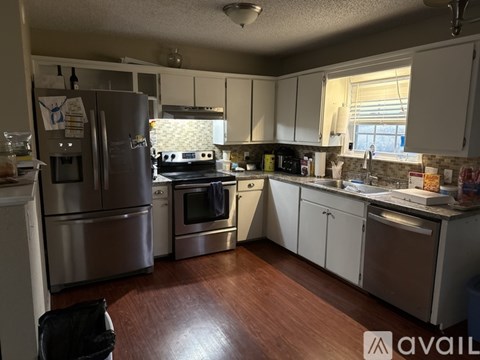 A kitchen with a refrigerator, oven, and sink.
