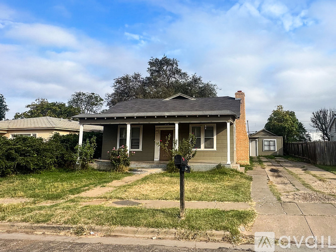 A house with a grey front porch and a mailbox on the sidewalk.