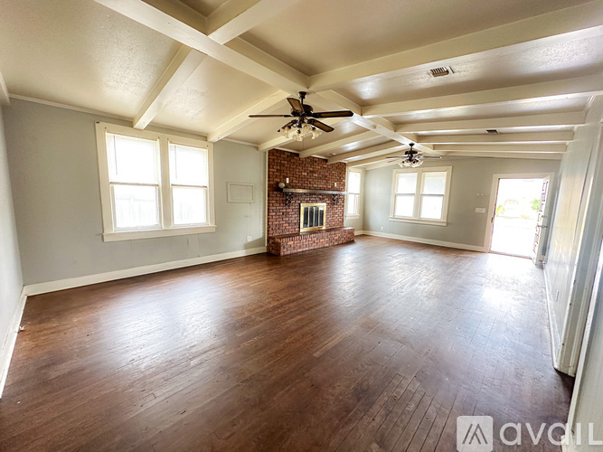 A room with wooden floors and a brick fireplace.