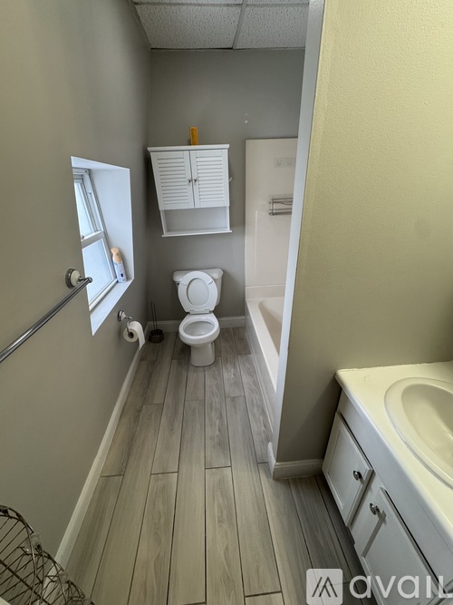 A bathroom with a toilet, sink, and a window.