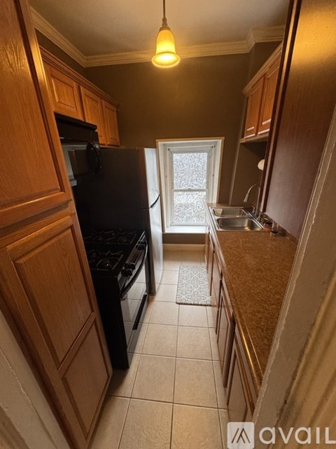 A kitchen with a black fridge and wooden cabinets.