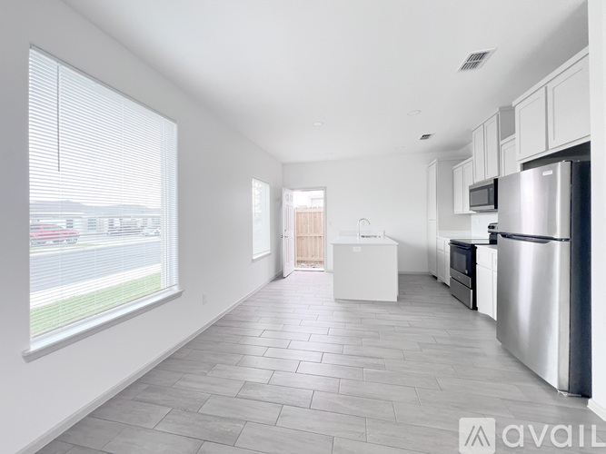 A kitchen with white cabinets and a refrigerator is available for rent.