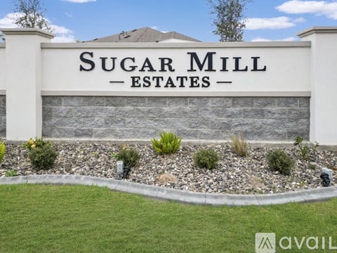 A sign that says Sugar Mill Estates in front of a building.