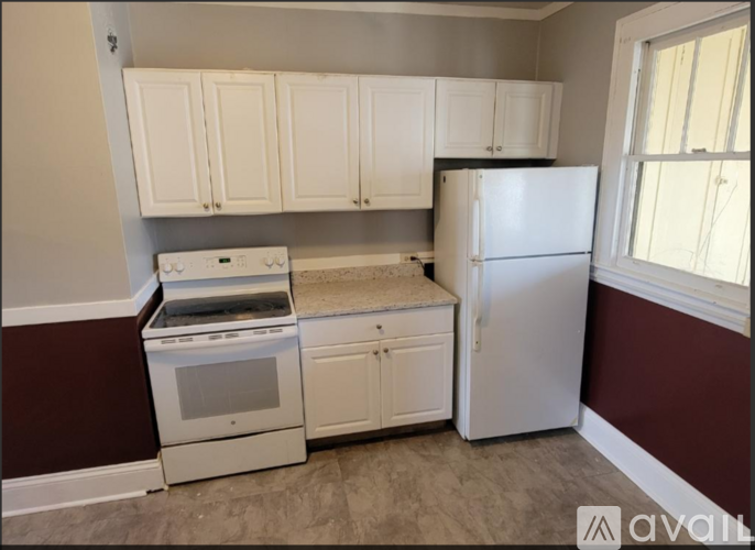 A kitchen with white cabinets and a white refrigerator.