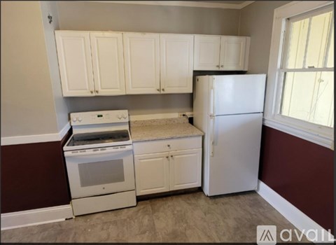A kitchen with white cabinets and a white refrigerator.