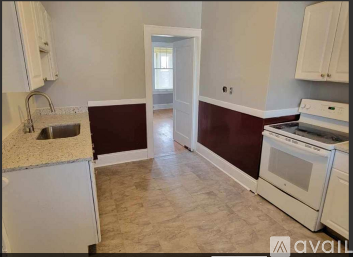 A kitchen with white appliances and a maroon backsplash.