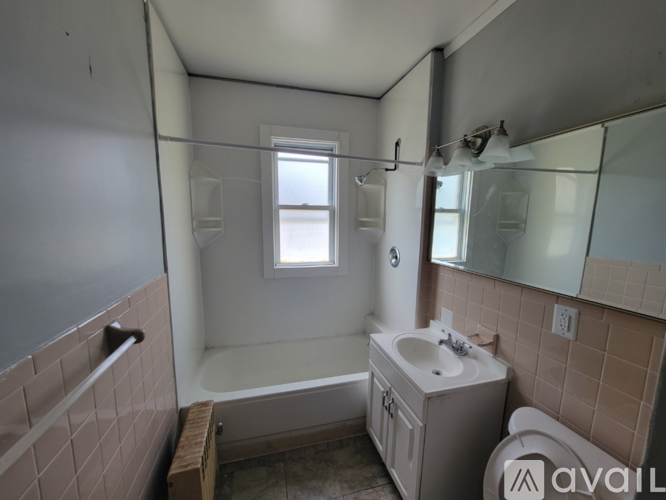 A bathroom with a tub, sink, mirror, and window.