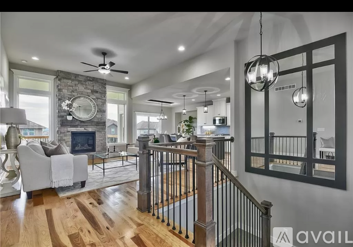 A spacious living room with a stone fireplace and a ceiling fan.