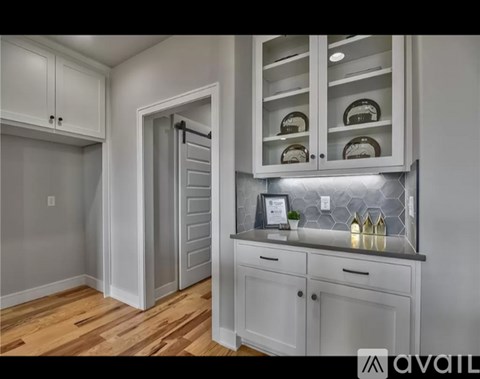 A kitchen with white cabinets and a wooden floor.