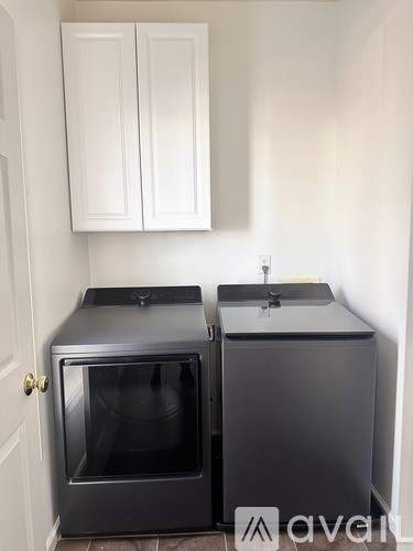 Two black ovens are in a kitchen with white cabinets.