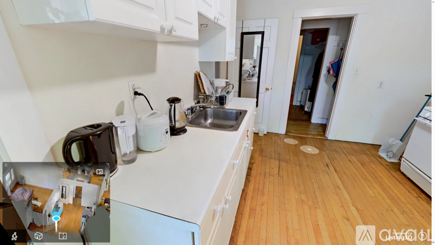 A kitchen with white cabinets and a wooden floor.