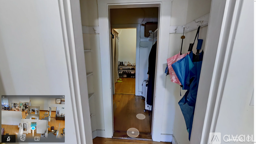 A view of a hallway with a doorway leading to a room with a bed and a hanging laundry basket.